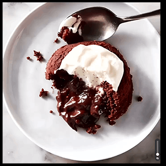 A rich chocolate lava cake with a molten center served with whipped cream and chocolate sauce drizzled on top